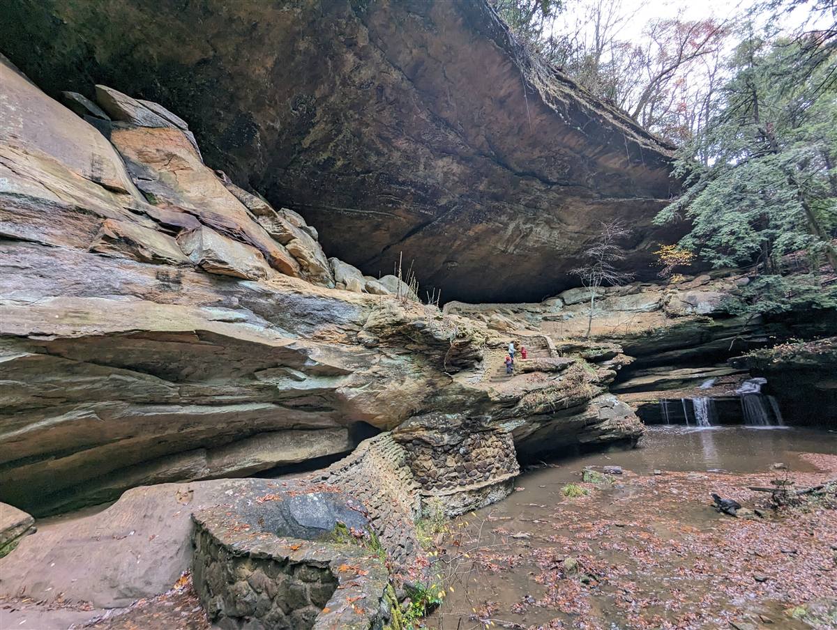 Sandstone cliffs and a small waterfall under a rock overhang
